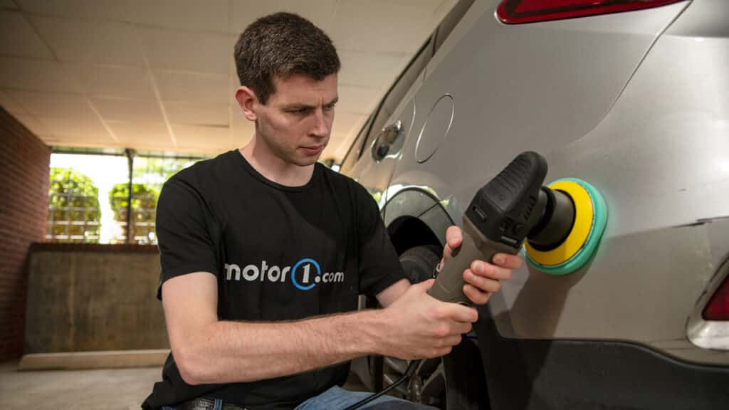 Serious Man in black T-shirt using polisher with felt pad on car