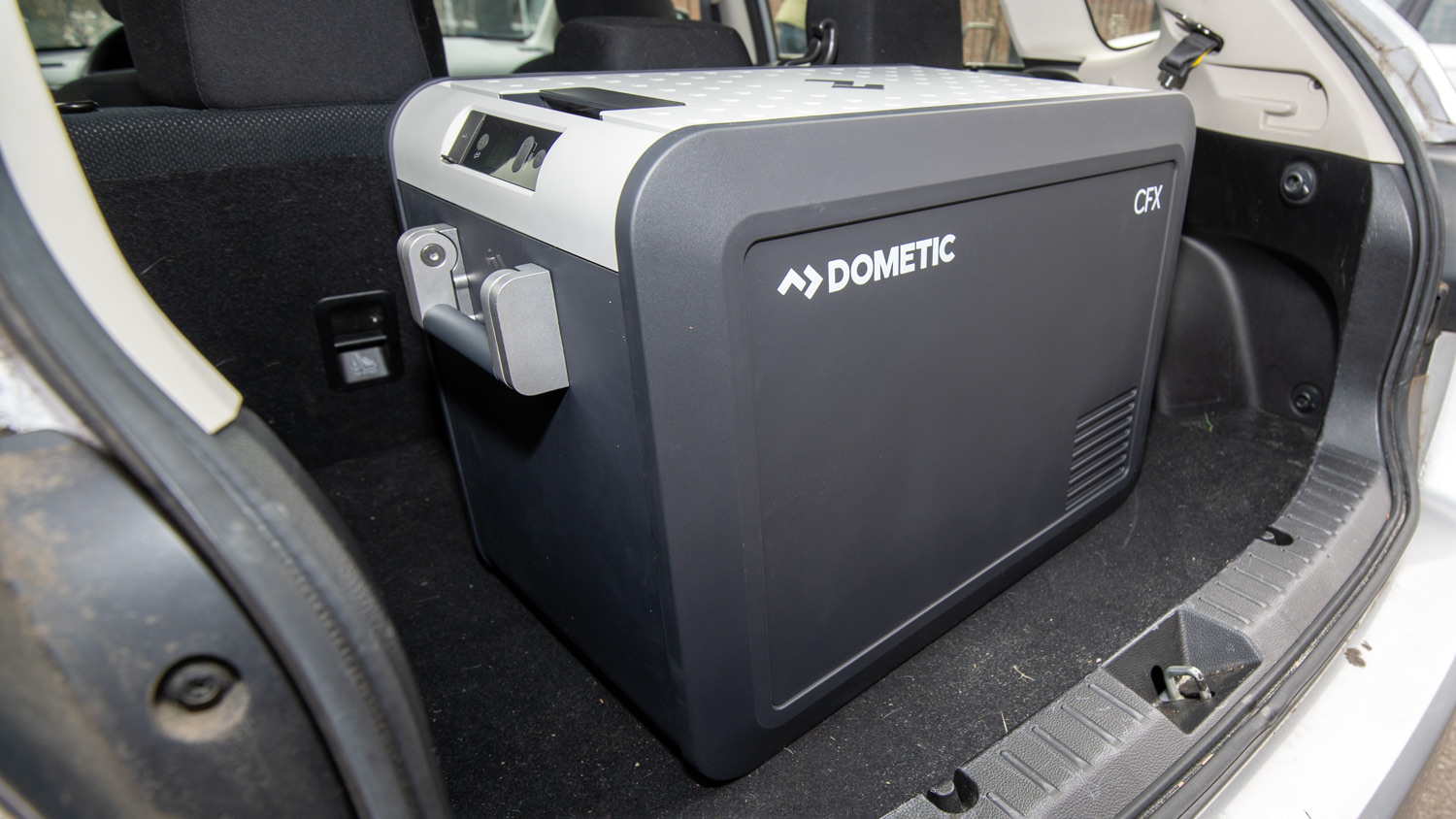 A Dometic CFX3 cooler sits in the open trunk of a car