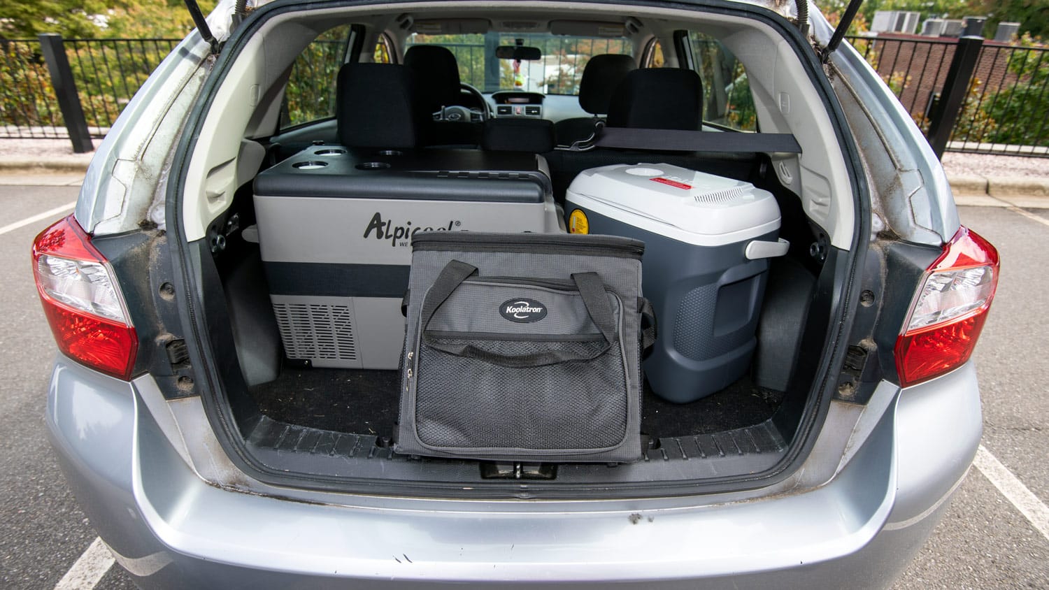 Picture of an open trunk of a car containing several 12V coolers