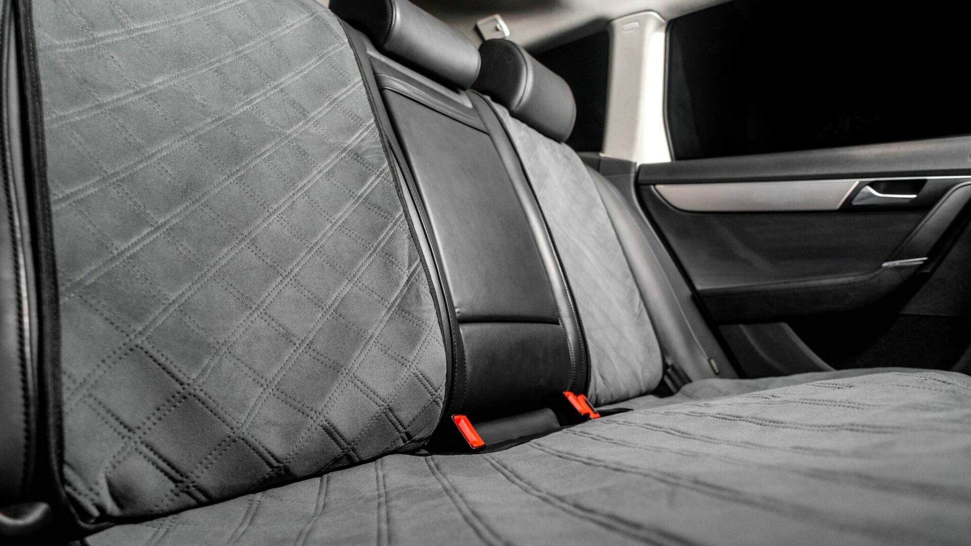 A gray car seat cover lines the back seat of a vehicle.