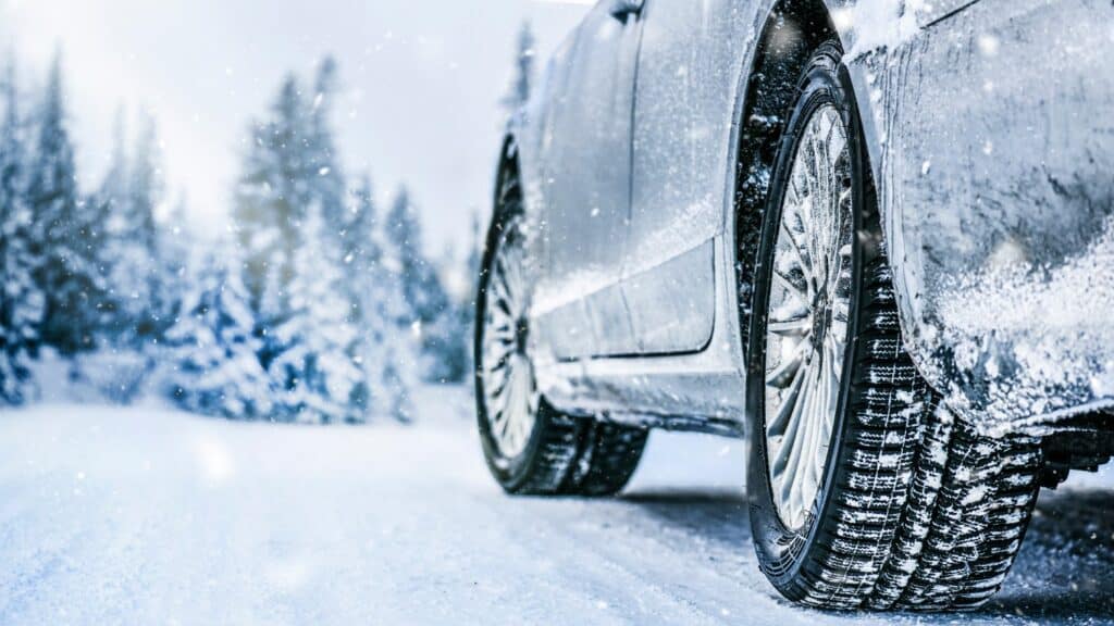 A vehicle's tires are caked with snow.